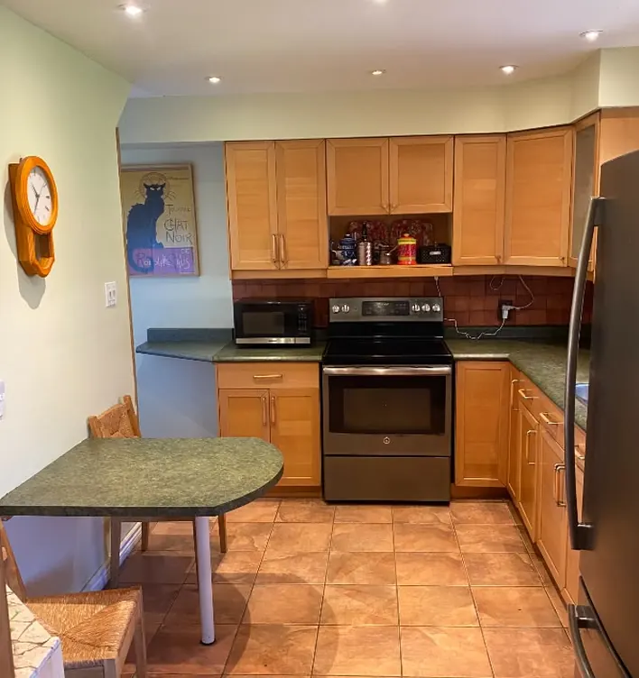 Before: kitchen with green laminate countertops and a matching breakfast bar