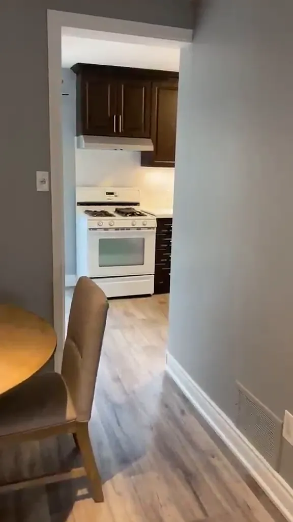 Hallway with new light plank flooring leading into an updated kitchen